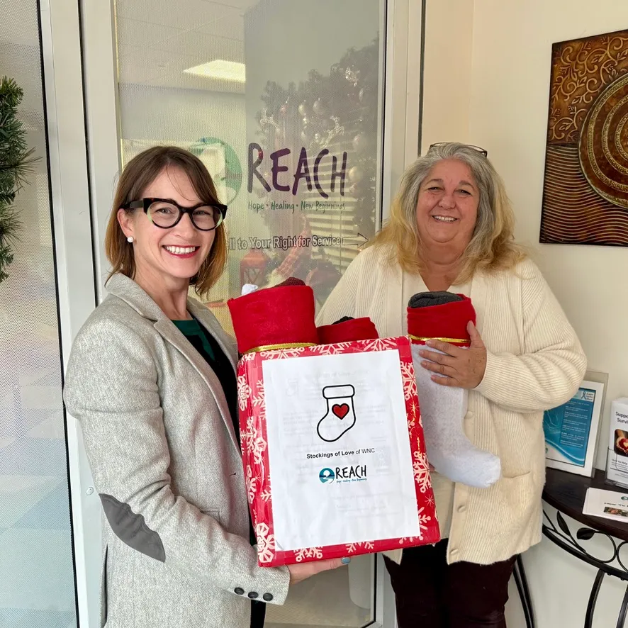 Two women holding a box of stockings at REACH of Haywood County