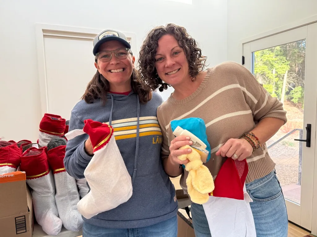 Two volunteers smiling as they fill stockings