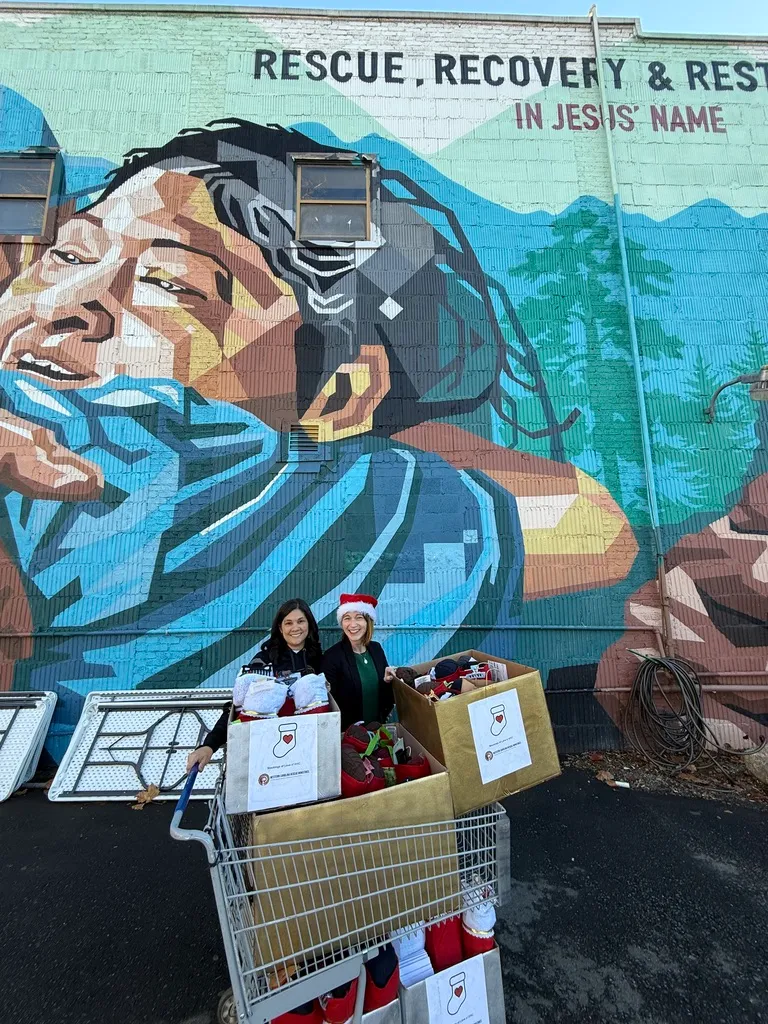A shopping cart of stockings for Cleveland County Rescue Mission in front of a mural reading “Rescue, Recovery & Restoration in Jesus’ Name”